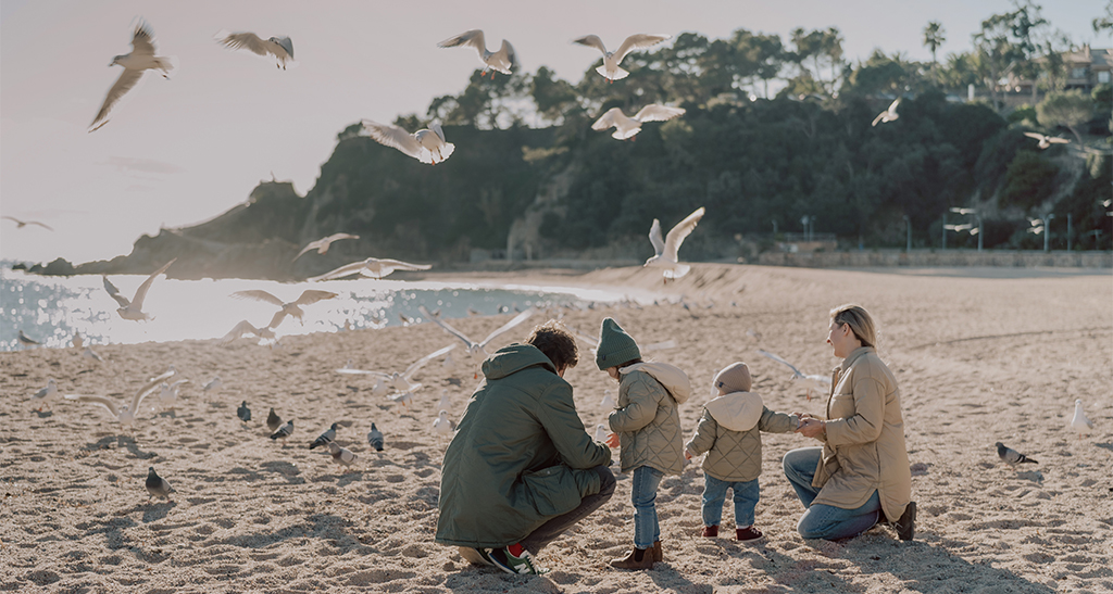 Family on the beach feeding birds on Costa Brava