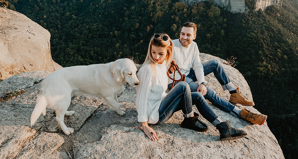 Vlad and Nastya with a dog sitting on the top of rock